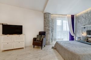 Schlafzimmer mit einem Bett, einem TV und einem Stuhl in der Unterkunft Black & White Apartment near Akropolis in Vilnius