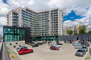 ein großes Gebäude mit Autos auf einem Parkplatz in der Unterkunft Black & White Apartment near Akropolis in Vilnius