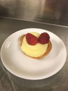 a white plate with a dessert with raspberries on it at Hotel Ragno D'Oro in Sottomarina