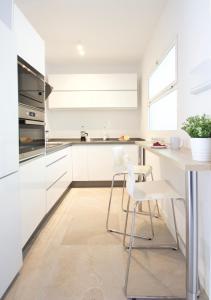 トレモリノスにあるHip & Cozy 2 room aptの白いキャビネット、テーブルと椅子付きのキッチンが備わります。