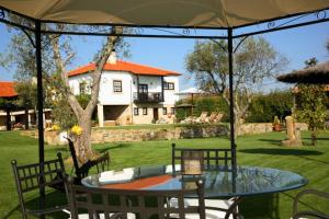 een tafel en stoelen onder een paraplu in een tuin bij Casa do Meio do Povo - Turismo de Habitação in Chaves