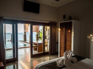 un dormitorio con cisnes en una cama con vistas al océano en Amed Beach Villa, en Amed