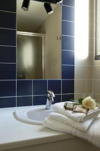 ein Bad mit einem Waschbecken, Handtüchern und einem Spiegel in der Unterkunft Hotel Canal Aigues Mortes in Aigues-Mortes