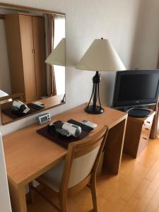 Pokój z biurkiem z lampką i telewizorem w obiekcie Accecss Tenjin w mieście Fukuoka
