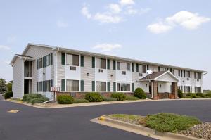 a large white building with a parking lot at Super 8 by Wyndham Tomah Wisconsin in Tomah