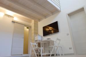 Cette chambre dispose de chaises blanches et d'une télévision murale. dans l'établissement ArcoSalento, à Galatina