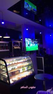 eine Bar mit einem TV und einem Kühlschrank mit Getränken in der Unterkunft منازل الساهر للوحدات السكنية فرع 1 in Al Qunfudhah