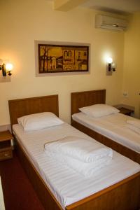 two beds in a room with two lamps on the wall at HOTEL T23 srl in Iaşi
