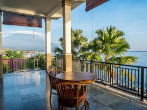 una mesa y sillas en un balcón con vistas al océano en Amed Beach Villa, en Amed