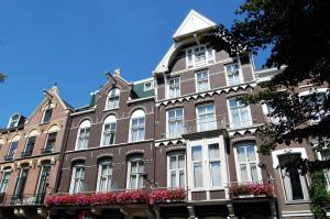 een groot bakstenen gebouw met bloemen ervoor bij Prinsenhotel in Amsterdam