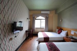 a hotel room with two beds and a flat screen tv at Chiayi Crown Hotel in Chiayi City