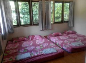 two beds sitting in a room with windows at Villa Triniti Blok i-35 in Bandung
