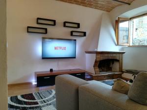 a living room with a couch and a tv on the wall at Casa Volterra in Volterra