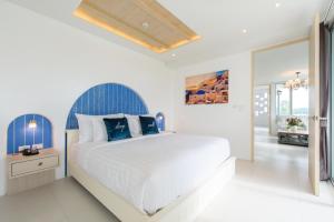a white bedroom with a large bed with blue accents at Costa Village Bangsaray in Bang Sare
