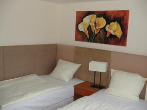 アッシャースレーベンにあるMotel Monteurの壁に絵画が飾られた部屋のベッド2台