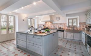 a large kitchen with white cabinets and a large island at Château des Demoiselles in La Motte