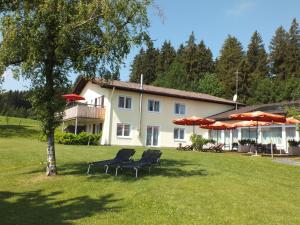 ein Haus mit zwei Stühlen und Sonnenschirmen in einem Hof in der Unterkunft Gästehaus Pension Bergwald in Scheidegg