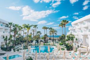 a view of the resort pool with chairs and palm trees at Iberostar Selection Marbella Coral Beach in Marbella