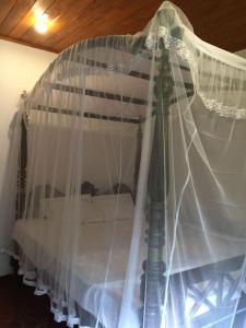 ein Himmelbett mit weißen Vorhängen darauf in der Unterkunft Green Herbal Ayurvedic Eco-Lodge in Galle