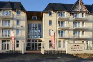 un gran edificio con un cartel delante en Domitys La Plage de Nacre, en Courseulles-sur-Mer