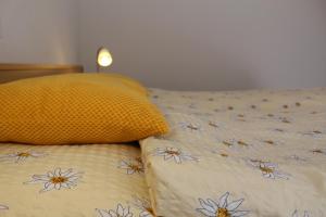 Una cama con una almohada amarilla con flores. en Haus Mondelli, en Saas-Almagell