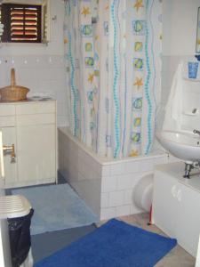 a bathroom with a shower curtain with a toilet and a sink at Apartments Adria Blue in Jelsa