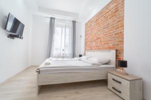 - une chambre avec un lit et un mur en briques dans l'établissement White Vision Apartment, à Carolinensiel