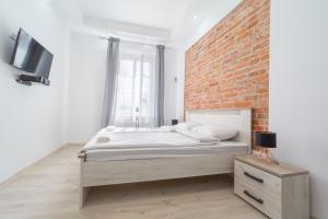 a bedroom with a bed and a brick wall at White Vision Apartment in Opole