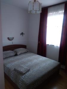 sypialnia z łóżkiem i oknem z zasłonami w obiekcie Apartman Edin w mieście Umag