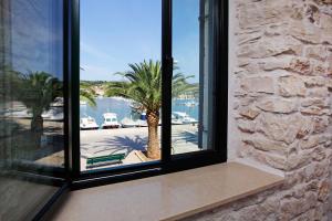a window with a view of a marina with a palm tree at Boutique rooms Kastel Ismaeli in Vela Luka
