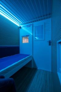 貝加莫的住宿－Resting Pods - ZzzleepandGo BGH Bergamo Hospital，一间蓝色的房间,在一扇门的房间里设有长凳