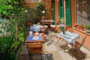 a patio with tables and chairs in a garden at Hotel Lydia in Alassio