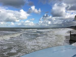 - une vue sur l'océan avec une planche de surf sur la plage dans l'établissement La Cornaline 1, à Cabourg
