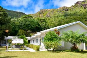a white house with a mountain in the background at HideAway in Anse Possession