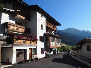 un edificio blanco con balcones de madera y flores. en Quality Hosts Arlberg - Haus Pepi Eiter en Sankt Anton am Arlberg