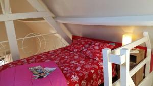 een kleine zolderkamer met een rood bed en een ladder bij Gite Le Bois Roger in Widehem