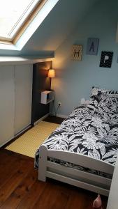een slaapkamer met een bed met een zwart-wit dekbed bij Gite Le Bois Roger in Widehem