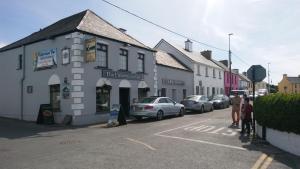 uma rua com carros estacionados em frente a um edifício em John Morgans House em Portmagee