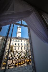 ein Fenster mit Blick auf ein Gebäude mit einem Uhrturm in der Unterkunft V.I.P.Apartmens Rynok Sqr.19 in Lwiw