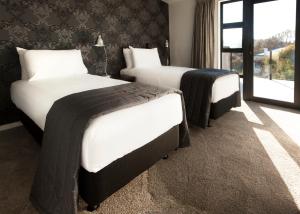 two beds in a hotel room with a window at Apartments on Upton in Wanaka