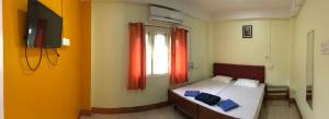 a bedroom with a bed and a window with red curtains at Urbban Castle in Port Blair