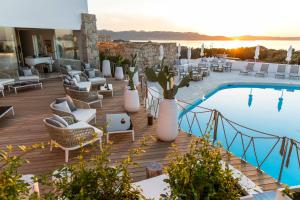 a resort with a pool and a deck with chairs at Hotel Grand Relais Dei Nuraghi in Baja Sardinia