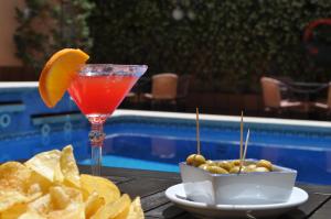 a drink and chips on a table next to a pool at RVHotels Mar de Tossa in Tossa de Mar