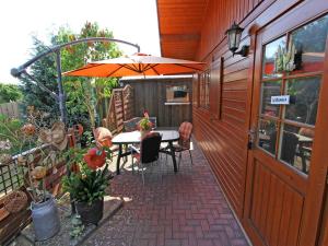 KargowにあるBlockhaus Kargow SEE 9651のパティオ(オレンジのパラソル、テーブル、椅子付)