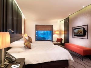 a hotel room with a large bed and a red chair at Sama Sama Hotel KLIA in Sepang