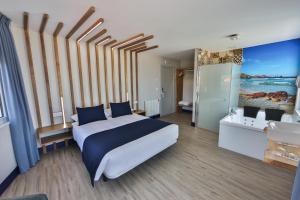 a bedroom with a large bed and a bathroom at Playa de Camariñas in Camariñas