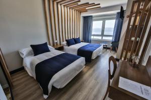 una habitación de hotel con dos camas y una mesa en Playa de Camariñas, en Camariñas 27 fotos más