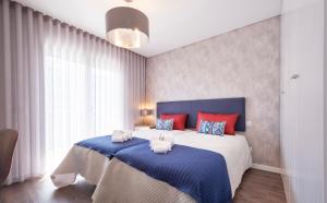 a bedroom with a large bed with blue and red pillows at Alto das Nogueiras House Fátima in Fátima +46 photos