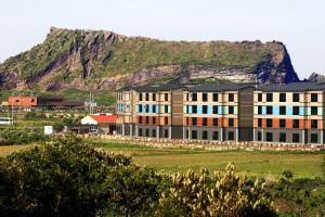 a large building with a mountain in the background at Jeju Stay in Sungsan in Seogwipo