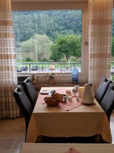 un tavolo da pranzo con sedie e una grande finestra di Wein- und Gästehaus St. Aldegundishof a Sankt Aldegund